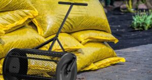 Black Compost Spreader With Yellow Bags Of Compost